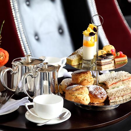Macdonald Bath Spa Hotel Exterior foto The photo depicts an elegantly arranged afternoon tea setting. There is a tiered stand filled with a variety of treats, including scones, sandwiches, and small desserts like cakes and pastries. Accompanying this is a teapot and a cup on the table, su