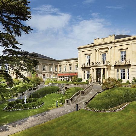 Macdonald Bath Spa Hotel Exterior foto The photo shows a grand building, likely a hotel or estate, surrounded by well-manicured gardens and lawns. The architecture appears elegant, with multiple stories and large windows. There are steps leading up to the entrance, and the setting include