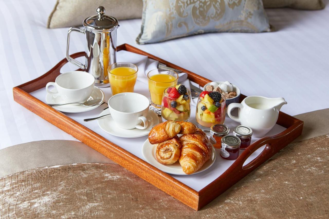Macdonald Bath Spa Hotel Exterior foto The photo shows a wooden tray arranged with a delightful breakfast spread. On the tray, there are two cups, a coffee pot, and several glasses of orange juice. There's also a small bowl of mixed fruit, featuring various colorful pieces. Additionally, 