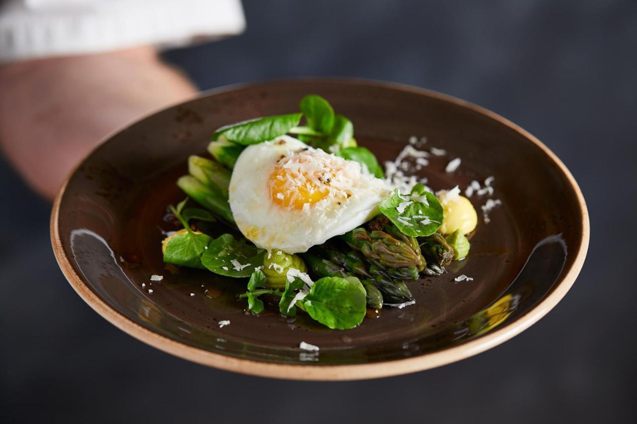 Macdonald Bath Spa Hotel Exterior foto The photo shows a plate of beautifully arranged food, featuring a poached egg on top of a mix of fresh greens. The greens include asparagus, lettuce, and possibly some herbs, garnished with a sprinkle of grated cheese or a similar topping. The dish i