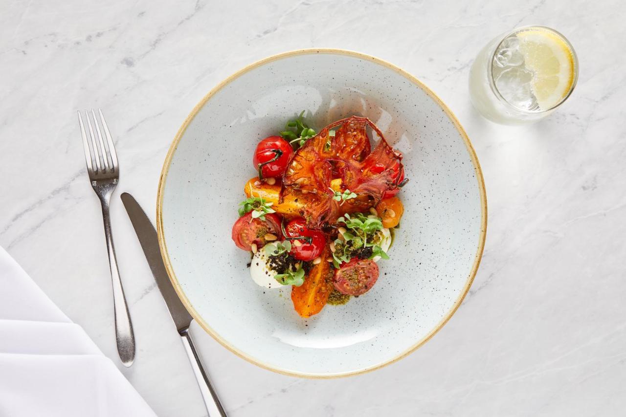 Macdonald Bath Spa Hotel Exterior foto The photo shows a beautifully arranged plate of food. The dish features a mix of colorful ingredients, including roasted or grilled vegetables, likely bell peppers and tomatoes, along with fresh greens. There are also some circular slices of another 