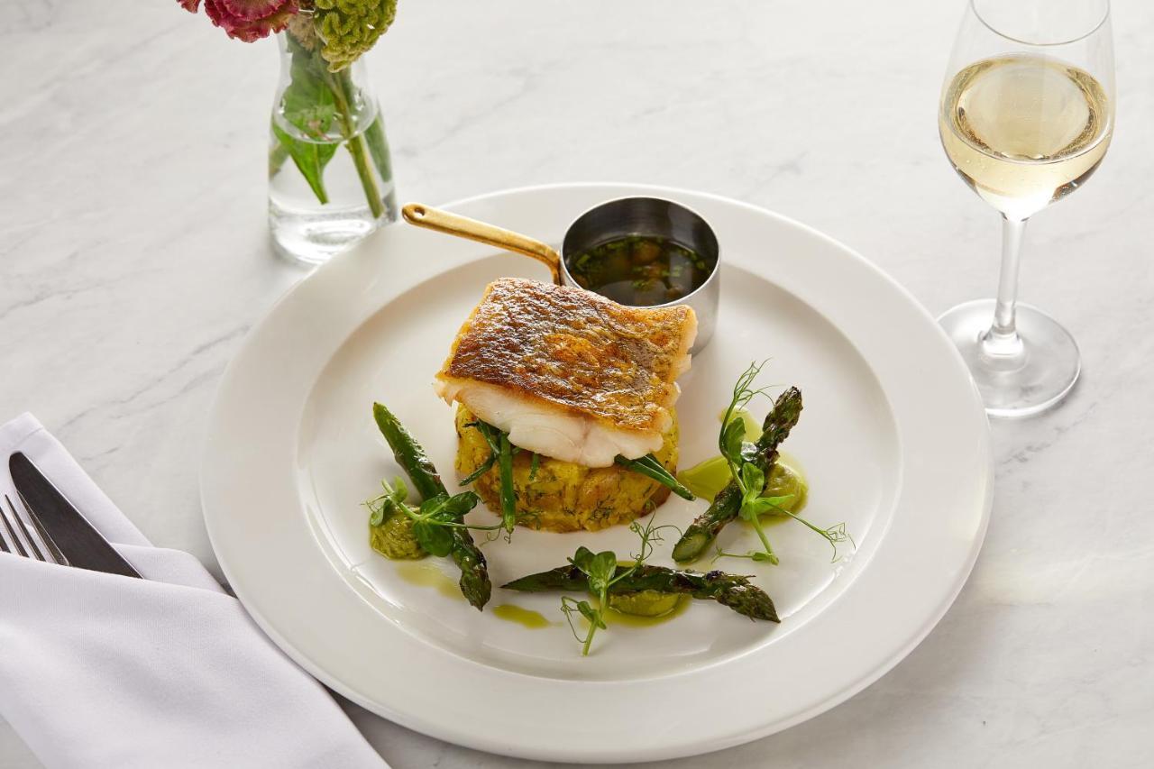 Macdonald Bath Spa Hotel Exterior foto The photo showcases a beautifully plated dish featuring a piece of fish, likely with a crispy skin, resting on a bed of what appears to be a savory cake or puree. Surrounding the fish are fresh asparagus and garnishes, adding a touch of color and fre