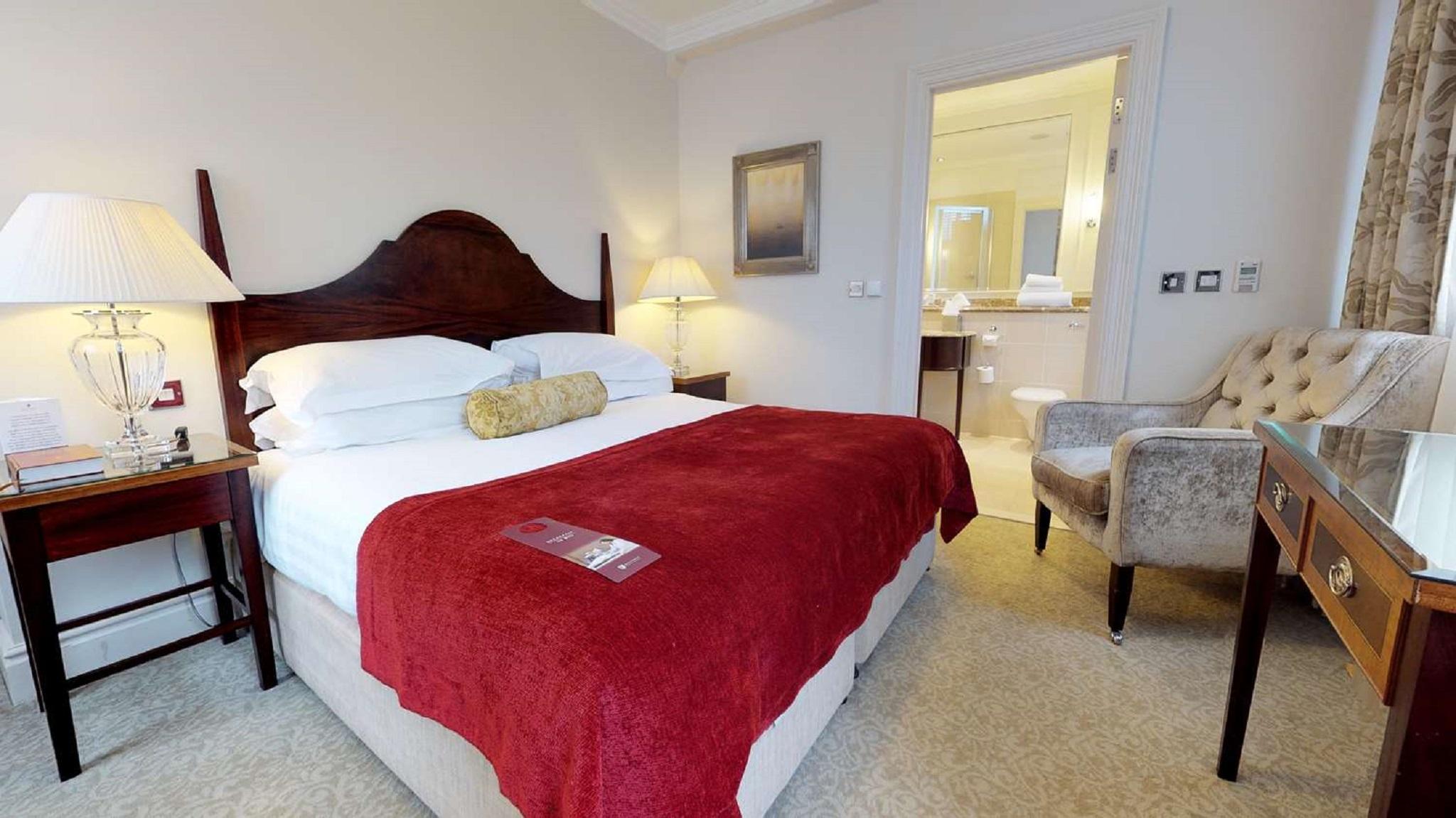 Macdonald Bath Spa Hotel Exterior foto The photo shows a well-furnished hotel room. In the center, there is a large bed with white linens and a red throw blanket. A decorative pillow is placed on the bed. On either side of the bed, there are bedside tables with lamps. To the right, there 