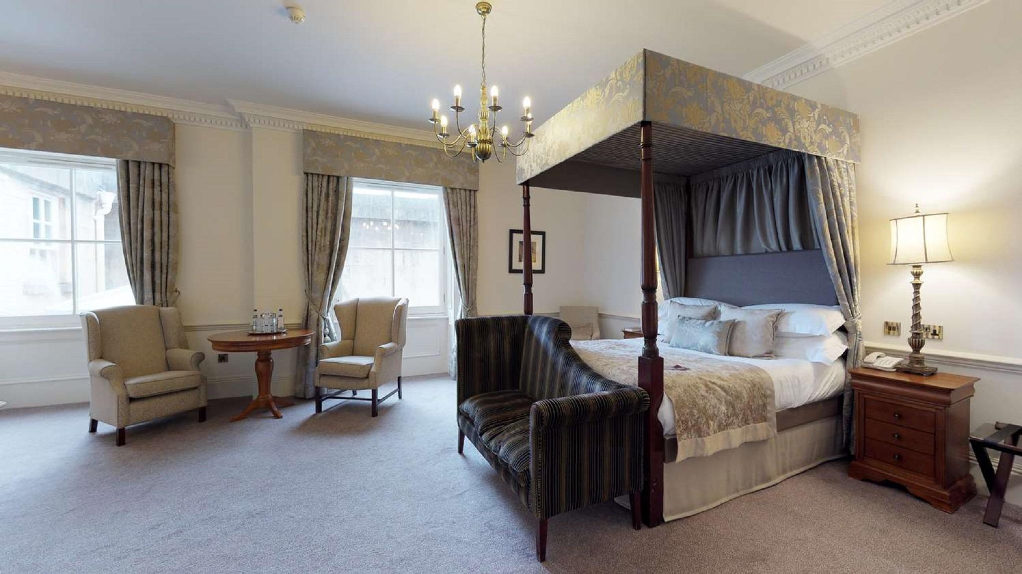 Macdonald Bath Spa Hotel Exterior foto The photo shows a stylish hotel room featuring a four-poster bed with a decorative canopy. The bed is positioned prominently in the center, surrounded by plush bedding. To the side, there are two armchairs with a small round table between them, creat