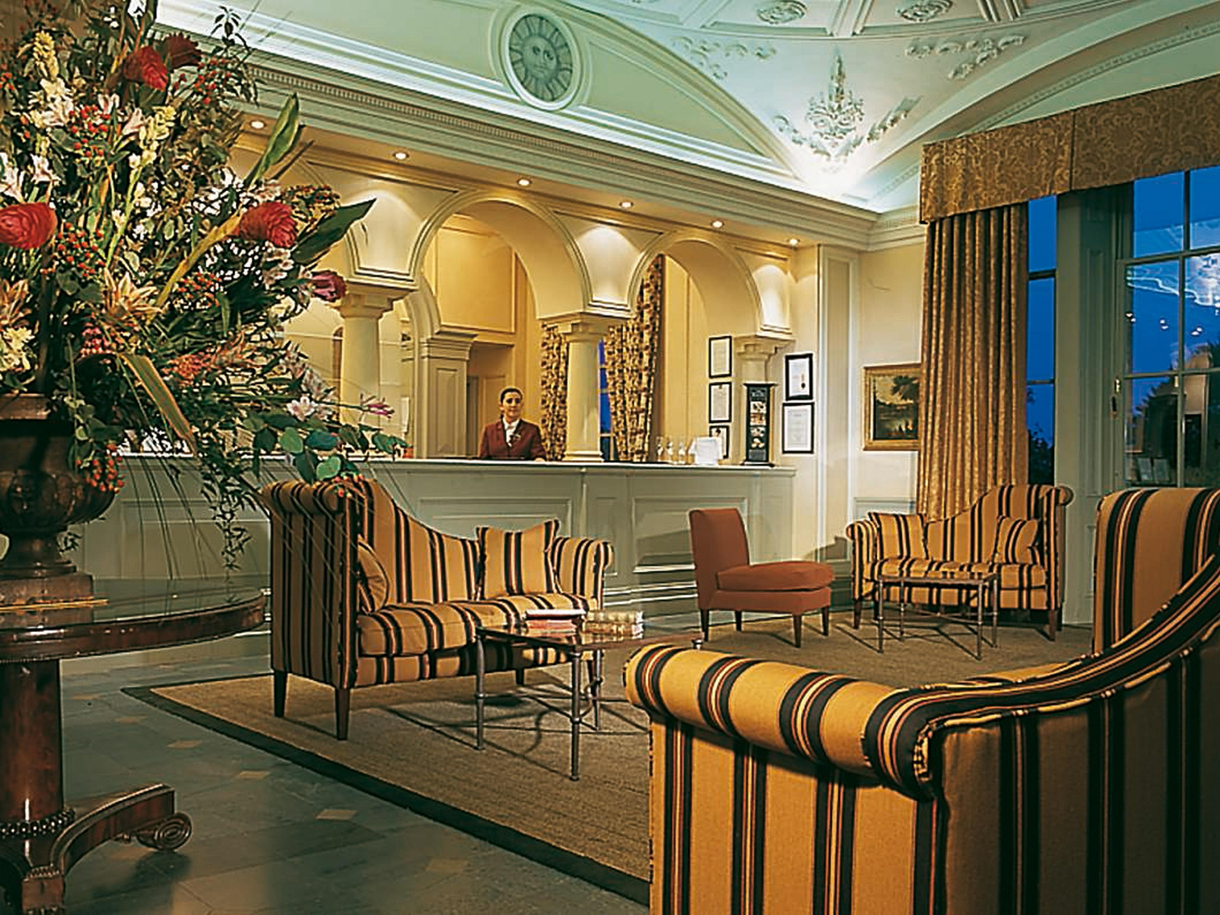 Macdonald Bath Spa Hotel Exterior foto The photo shows an elegant hotel lobby. The area features a reception desk with a staff member behind it. Surrounding the reception are comfortable seating arrangements, including striped armchairs and a brown chair. A large vase with an elaborate fl