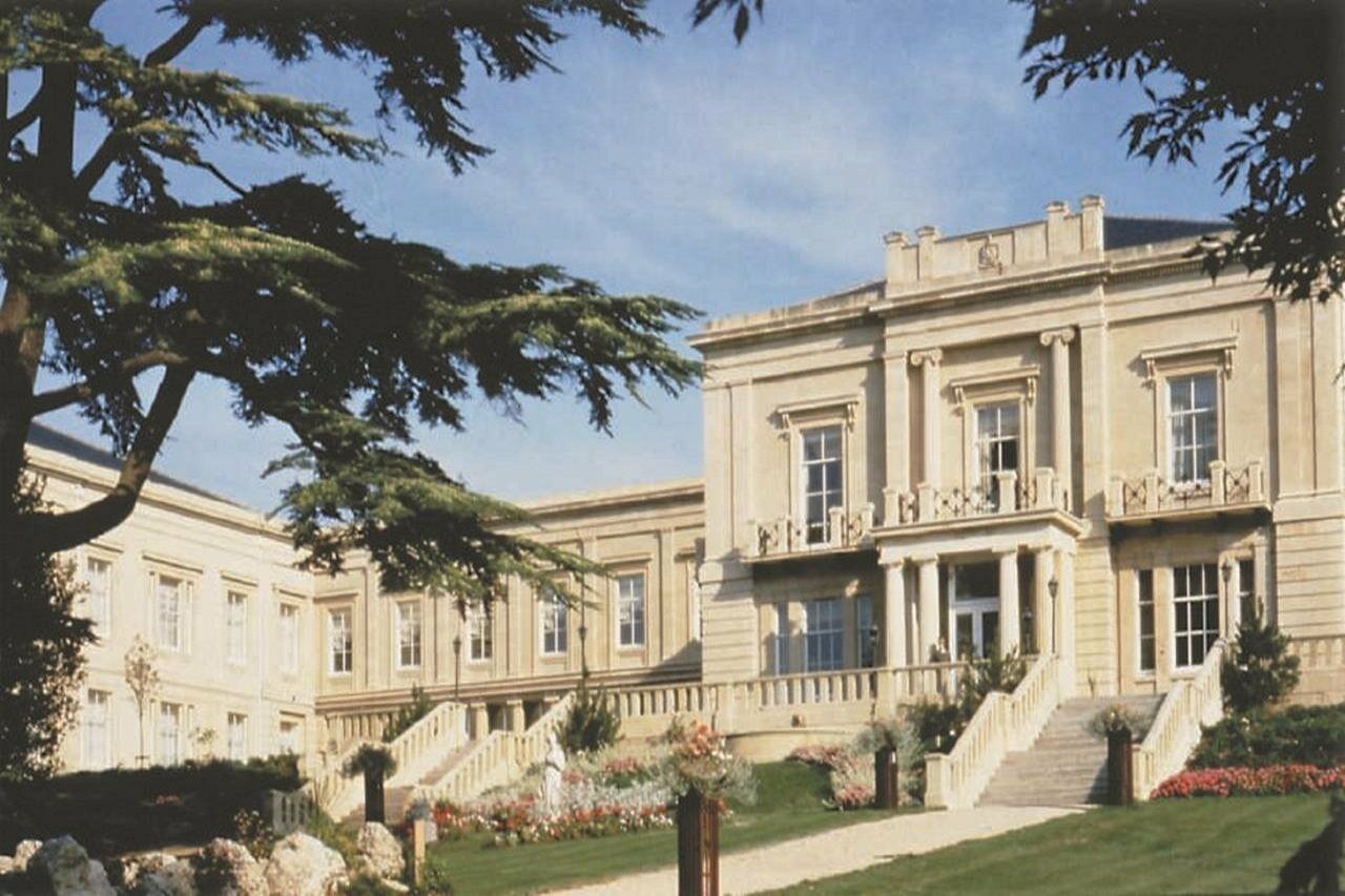 Macdonald Bath Spa Hotel Exterior foto The photo depicts an elegant, stately building characterized by classical architecture. It features a symmetrical facade with large windows and decorative balconies. The structure is complemented by a lush green lawn and landscaped gardens, enhancing